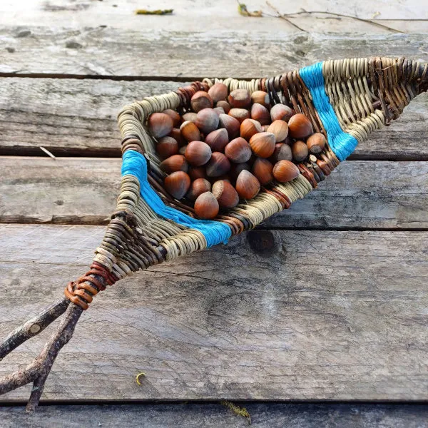 Corbeille rustique remplie de noisettes, posée sur des planches de bois