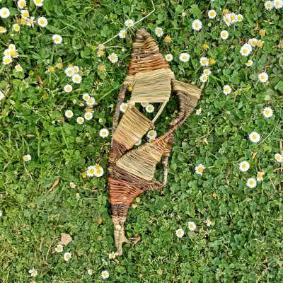 Création libre en forme de poisson stylisé, posée sur une pelouse fleurie de pâquerettes