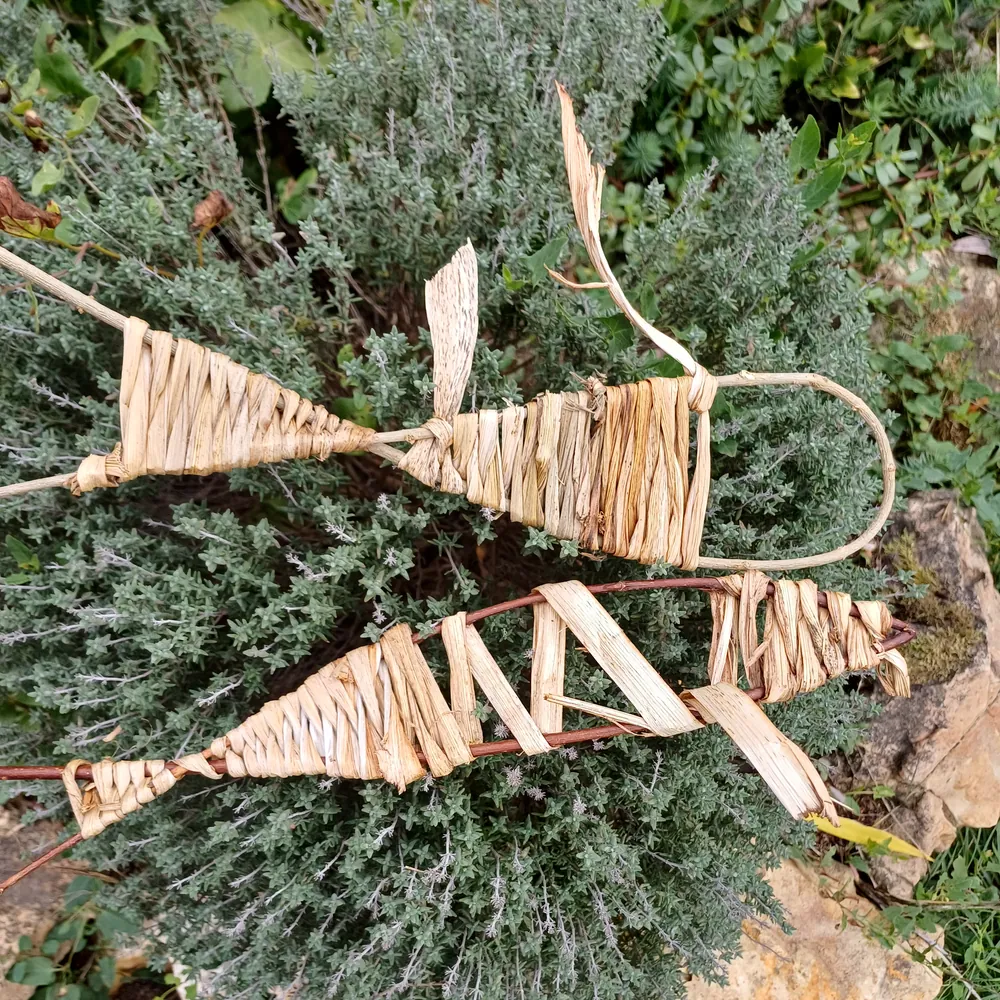 Deux poissons tressés en feuilles, posés sur un buisson de thym