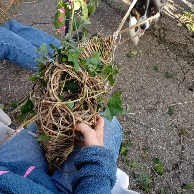 Un enfant tresse un nichoir rustique avec des branches et du lierre