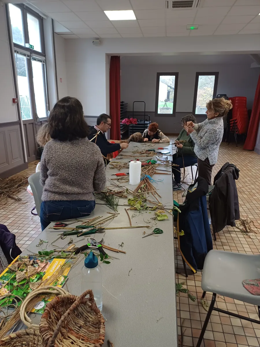 Participants autour d'une grande table couverte de végétaux, dans une salle